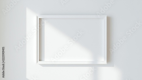 Empty horizontal picture frame hanging on a clean wall with soft natural sunlight shadow
