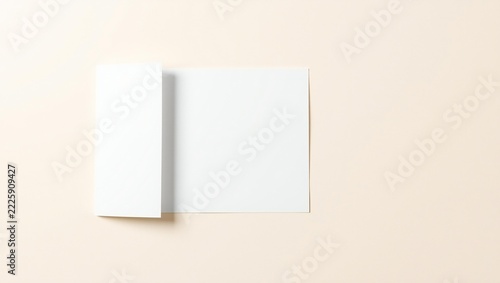 Blank white folded paper brochure flyer mockup on a soft beige background