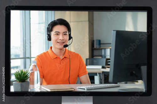 Smiling customer support representative with headset working remotely at modern office desk