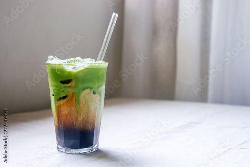 Iced matcha espresso coffee latte with beautiful swirl texture in a glass with copy space.