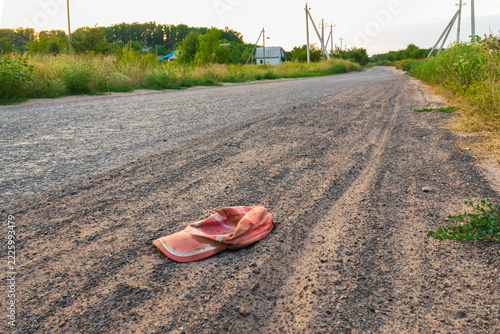 A dirty cap lies on the side of an empty country road