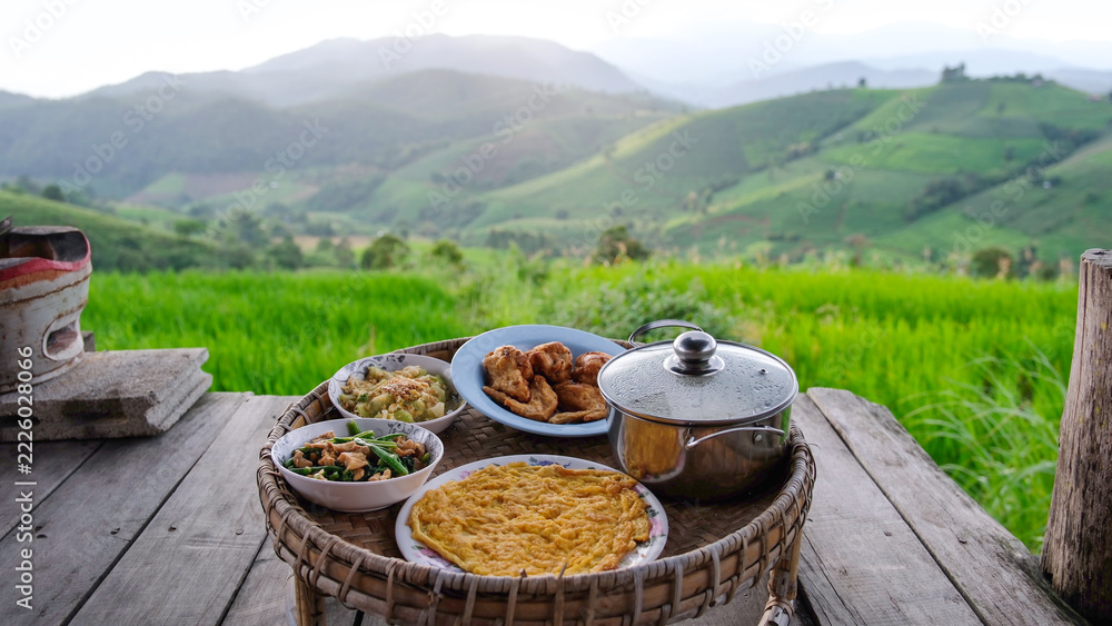 Naklejka premium A set of Thai traditional dining table with rice terrace and mountain views