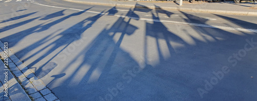 Long Shadows Of Flags Across An Urban Street At Sunrise Casting Silhouettes On Pavement