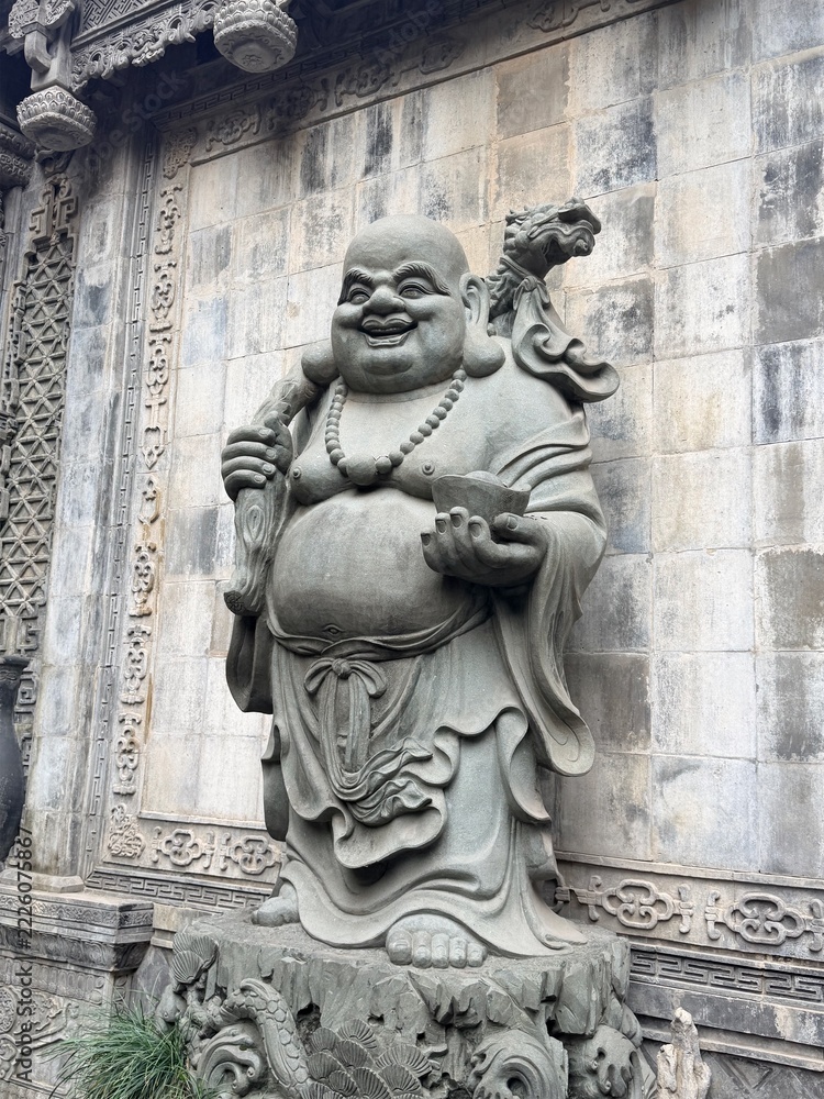 Fototapeta premium Smiling Buddha stone carving on an ornate temple wall in Chongqing, China