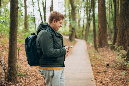 A man in a forest is looking for a way using a mobile navigator - to get lost in the forest. Male explorer looking for connection to the internet or using gps navigator app on phone