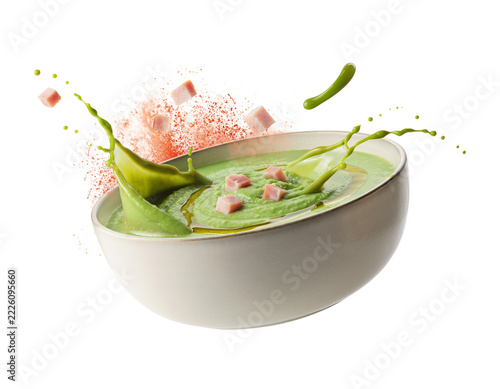 Vibrant green pea soup with ham cubes and dynamic splash