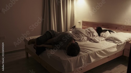 Emotionally exhausted man lying face down across the bed while his partner turns away, portraying relationship problems, emotional distance and tension in an everyday millennial home