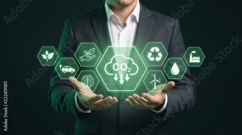 Businessman holding glowing green environmental icons demonstrating sustainable business practices