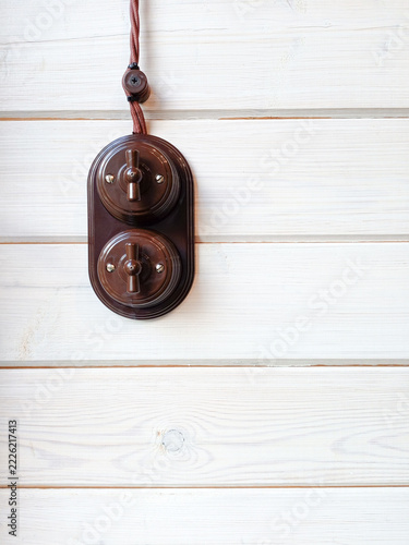 Vintage electric light switch hanging on a white wooden wall with copy space