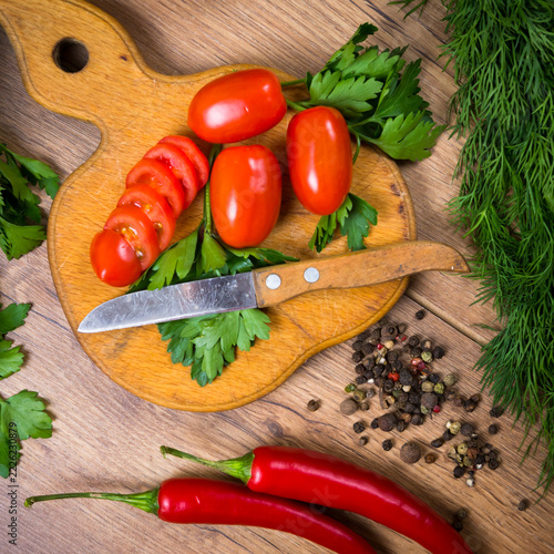 Preparing vegetables on a wooden cutting board with a knife and herbs in a kitchen setting