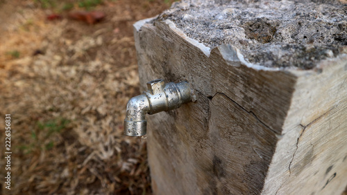 Metallic water tap installed on a rough stone block in an outdoor environment