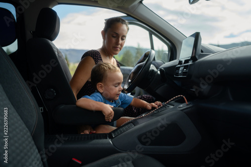 Mother supervising toddler exploring modern car interior