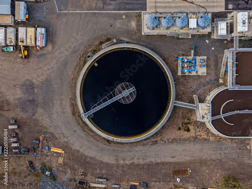 Aerial view of a circular wastewater treatment clarifier with industrial tanks and infrastructure in The Common, Queensland, Australia.