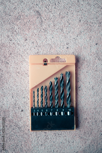 Set of woodworking drill bits in a yellow case on a concrete background with copy space