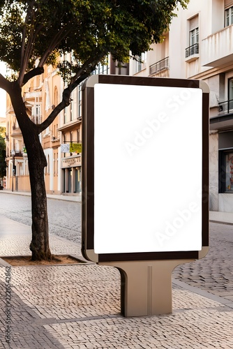Empty advertisement billboard on urban cobblestone sidewalk near buildings