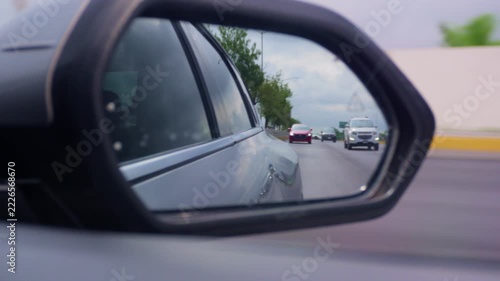 Cars driving reflected in a side view mirror during city commute