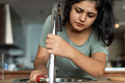 Wall Mural Focused woman fixing faucet photo