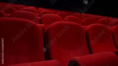 Empty red seats in a dark movie theater cinema auditorium