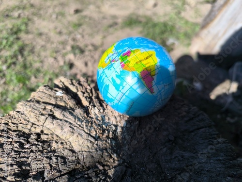 A colorful mini globe rests peacefully on a wooden surface outdoors.