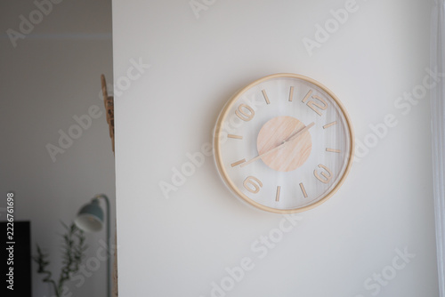 Round wall clock hangs on a white wall beside a doorway