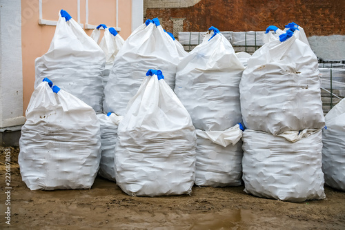 Large white bulk bags filled with paving stones at an urban construction site. Materials prepared for laying cobblestone streets, sidewalks and pedestrian areas during roadwork