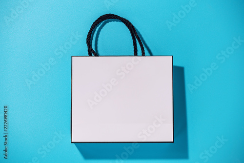 Empty white shopping bag on blue background, top view