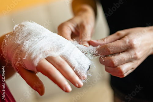 Hands applying sterile gauze bandage on injured wrist first aid concept