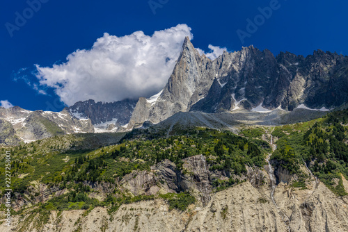 Impressive view of Les Drus, a dramatic pair of granite peaks in the Mont Blanc massif of the French Alps near Chamonix. The iconic mountain formation rises above deep alpine valleys