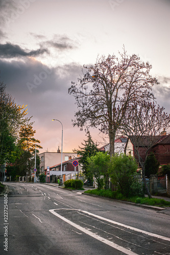 European suburban street with houses and autumn trees against a dramatic evening overcast sky
