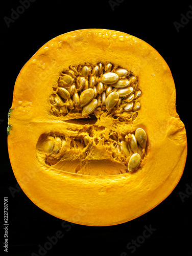 Close-Up Half Pumpkin With Seeds And Vibrant Orange Flesh On Black Background, Autumn Harvest Produce
