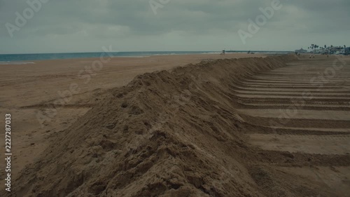 Long piles of sand form raised protective ridges on Newport Beach during storm preparation work.