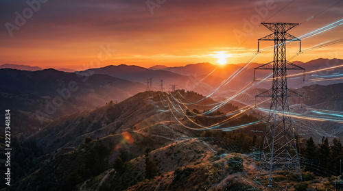 Electricity pylons with glowing digital data streams across mountain landscape at sunset, ideal for energy supply, smart grid and telecommunication promotion