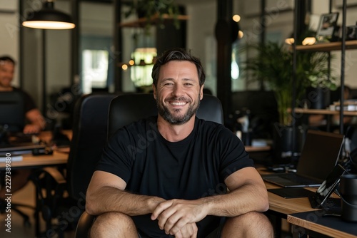 Friendly male entrepreneur smiling while sitting at his desk in a casual startup office space