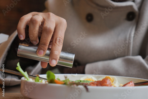 a person using a stainless steel one-handed push-action salt or pepper grinder