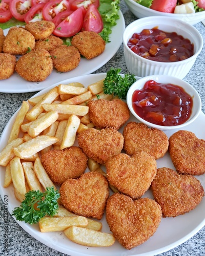 Heartshaped savory bites accompany crispy fries and refreshing tomato slices.