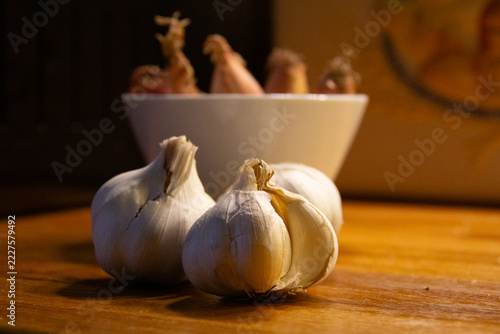 Close up of garlic bulbs on a wooden kitchen counter with shallots