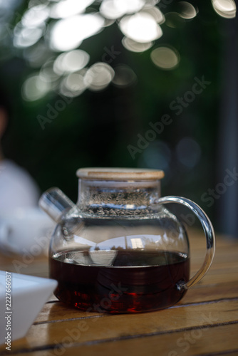 Glass Teapot with Dark Tea on Wooden Table Outdoors