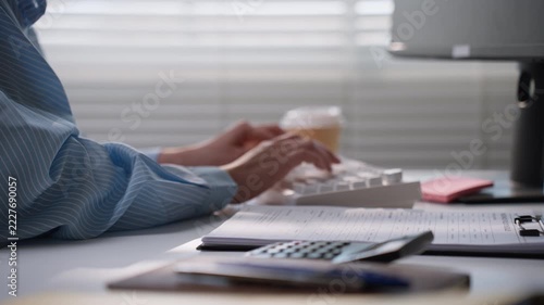 Business professional using a white computer keyboard at a desk with financial paperwork, illustrating accounting data entry, electronic record management, office productivity, and bookkeeping workflo