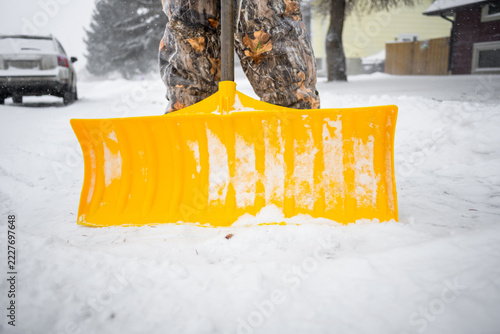 Snow removal with yellow shovel during winter storm