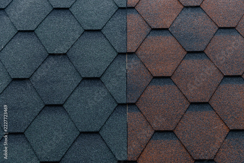 Hexagonal textured roofing tiles in contrasting dark gray and weathered brown tones arranged in a repeating geometric pattern, architectural surface background