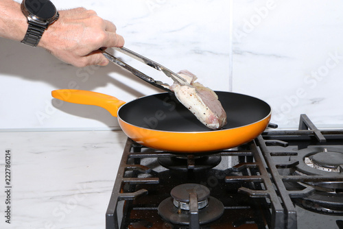 A close-up shot capturing the process of cooking meat chops in a kitchen.