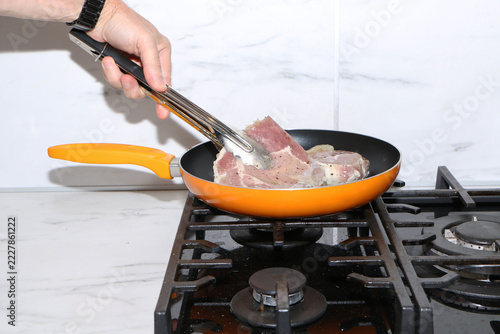 A close-up shot capturing the process of cooking meat chops in a kitchen.