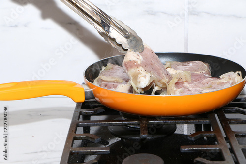 A close-up shot capturing the process of cooking meat chops in a kitchen.