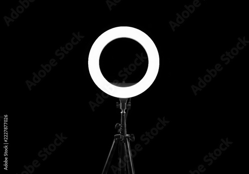 Bright led ring light glowing on a tripod stand against a dark background isolated on transparent background
