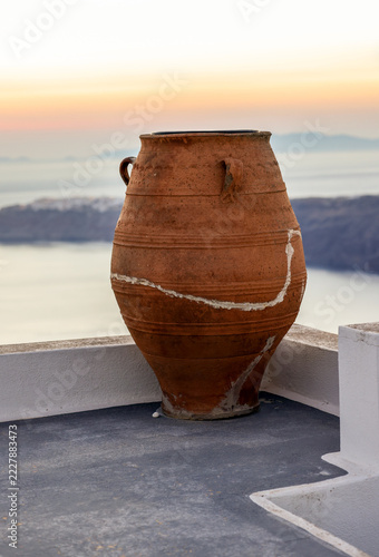 A repaired old jug on a terrace with a beautiful view of the sunset in Santorini. Greece