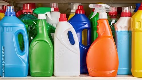 Colorful plastic bottles for household cleaning products arranged on shelf