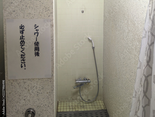 シャワー使用後は必ず止めてくださいの貼り紙 屋内プールのシャワーブースと混合水栓