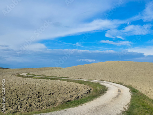 Winding dirt road through rolling hills of Val d'Orcia, Tuscany, Italy