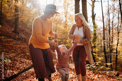 Joyful three generations of women having fun on an autumn walk in the forest.