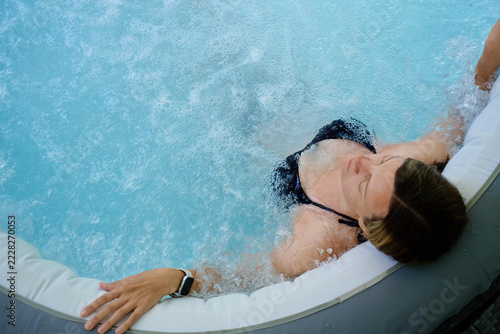 Woman relaxing in bubbling hot tub with eyes closed